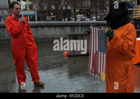 Janvier 11, 2018 - Londres, Royaume-Uni. 11 janvier 2018. Les combinaisons de saut orange et noir hoods debout dans un square à Trafalgar Square marquant 16 ans de la détention illégale et la torture au camp de Guantanamo Bay. Les noms des 41 détenus restants ont été lus, de nombreux détenus indéfiniment sans accusation ni procès, presque tous ceux qui ont été vendus aux Etats-Unis par des milices afghanes et les primes en espèces pour les militaires pakistanais avec aucune preuve réelle d'implication terroriste, mais dont la torture dans des prisons secrètes de la CIA à travers le monde avant l'arrivée à Guantanamo comme tout comme tout au long de leur détention n'y fait Banque D'Images