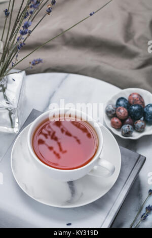 Tasse de thé noir sur un livre sur le plateau de marbre dans le lit au matin Banque D'Images