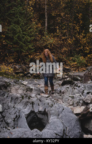 Red haired woman marche sur les rochers humides Banque D'Images