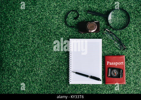 Appareil photo, loupe, boussole et passeport portable vide sur une herbe verte. concept Voyages et vacances Banque D'Images