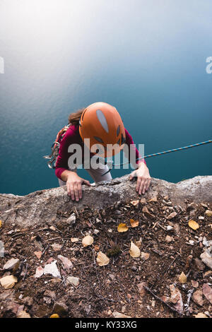 Rock climber atteindre sur la falaise Banque D'Images