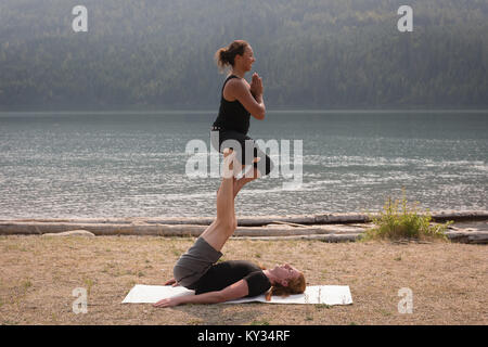 Les femmes pratiquant le yoga acro sport sur un terrain ouvert Banque D'Images