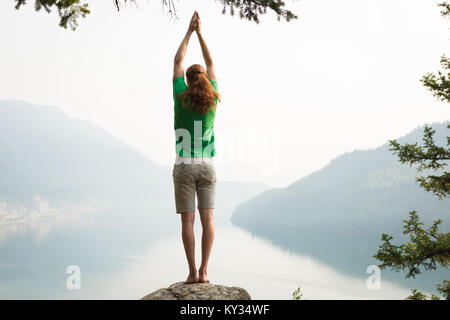 Fit man performing exercice s'étendant sur le bord d'un rocher Banque D'Images