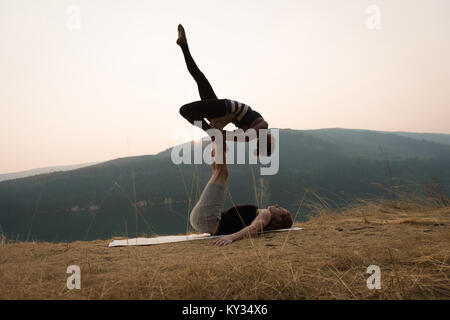 Sporty couple practicing yoga acro dans un terrain verdoyant Banque D'Images