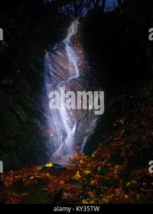 Cascade de nuit. Une pulvérisation d'eau en blanc sur une chute d'eau, l'eau mousseuse est tomber de rock moussues. Le spray créer au niveau de l'eau laiteuse et de gravier Banque D'Images