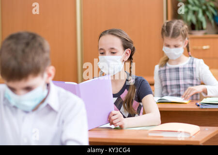 Les écoliers avec les masques de protection contre les virus de la grippe aviaire à leçon en classe Banque D'Images