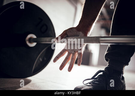 Close-up of a strong man's hands de talc se prépare à l'haltérophilie au garage de sport. Banque D'Images