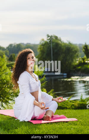 Femme assise en position du lotus sur la nature à l'extérieur. Sport, Fitness, mode de vie sain pendant la grossesse. Regarder la caméra. Banque D'Images