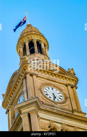 Tour de l'horloge de l'Hôtel de Ville, la ville de Sydney. Drapeau australien sur le dessus de la tour de ville historique Hall Building, ciel bleu. Banque D'Images