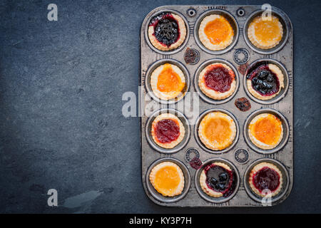 Tartelettes à la confiture faite maison cuit dans une plaque de cuisson sur ardoise. Vintage filtre appliqué Banque D'Images