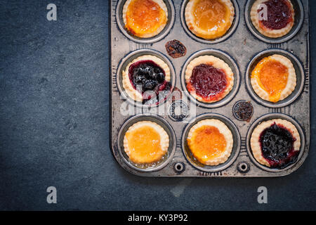 Tartelettes à la confiture faite maison cuit dans une plaque de cuisson sur ardoise. Vintage filtre appliqué Banque D'Images