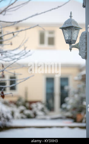 Un coup d'hiver lumineux de la capture d'un style traditionnel coach extérieur lanterne couverte de neige. Soft-focus contexte montre bien couverte de neige et jardin. Banque D'Images