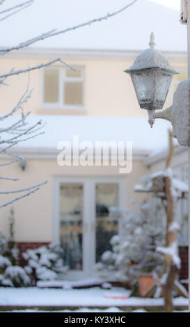 Un coup d'hiver lumineux de la capture d'un style traditionnel coach extérieur lanterne couverte de neige. Soft-focus contexte montre bien couverte de neige et jardin. Banque D'Images