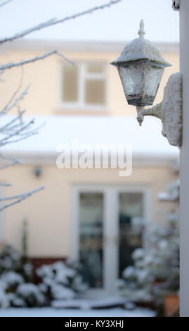 Un coup d'hiver lumineux de la capture d'un style traditionnel coach extérieur lanterne couverte de neige. Soft-focus contexte montre bien couverte de neige et jardin. Banque D'Images