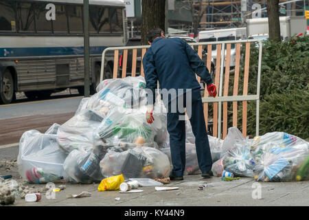 Un ouvrier d'entretien porte sur son pieux du bâtiment de déchets en attente de pick-up à New York, le Jeudi, Janvier 11, 2017. Comme la neige fond de notre récente tempête et des températures glaciales le ministère de l'assainissement commence à reprendre l'ensemble de la montagne d'ordures, aggravé par les arbres de Noël et de l'utilisation des déchets domestiques de cadeaux de Noël. (© Richard B. Levine) Banque D'Images