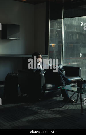 Businessman talking on phone while having coffee Banque D'Images