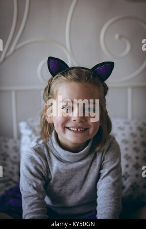 Portrait of smiling girl sitting on bed Banque D'Images