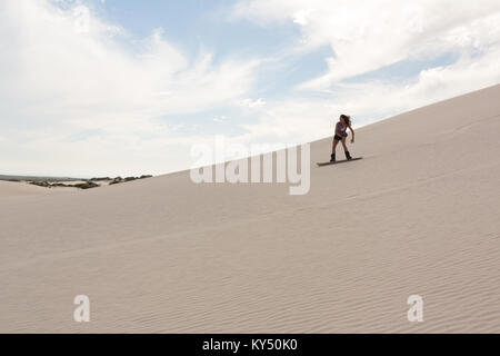 Femme sandboarding on sand dune Banque D'Images