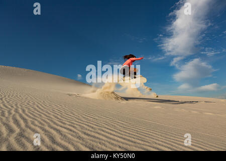 Femme sandboarding on sand dune Banque D'Images