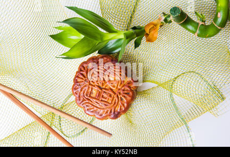 Gâteaux de lune chinois avec des baguettes de bambou et le bénéfice net et sur fond blanc Banque D'Images