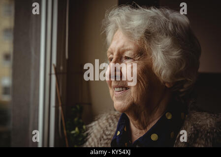 Smiling senior woman looking out de la fenêtre Banque D'Images