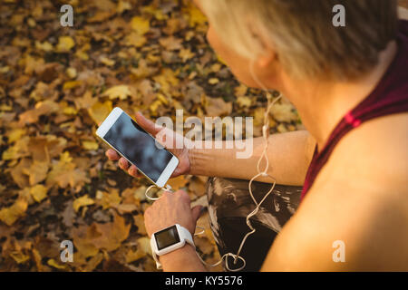 Senior woman listening to music in the park Banque D'Images