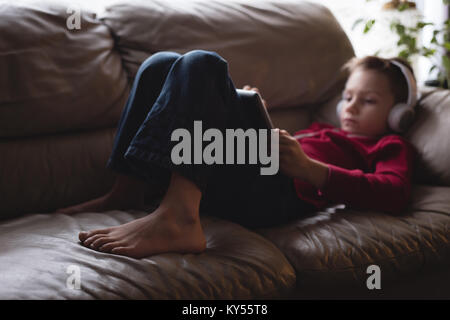 Boy using digital tablet avec des écouteurs dans la salle de séjour Banque D'Images