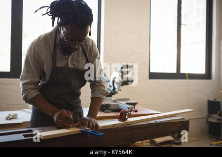 Carpenter measuring planche en bois avec l'échelle Banque D'Images