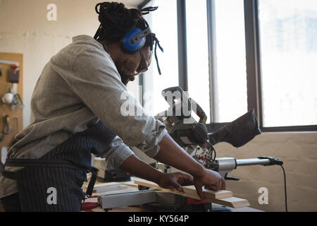 Carpenter avec planche en bois de coupe scie électrique Banque D'Images