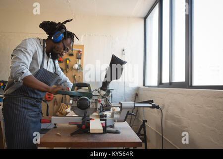 Carpenter avec planche en bois de coupe scie électrique Banque D'Images