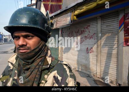 Srinagar, au Cachemire. 13 Jan, 2018. Un Kashmirn policier montent la garde devant les boutiques fermées pendant un couvre-feu dans la région de Srinagar, Cachemire administré par Kashmirn. Les autorités ont imposé des restrictions de Srinagar, en plus de parties de civil lines le samedi à la suite de grève déclenchée par les séparatistes à l'encontre de civils dans la vallée. Credit : Saqib Majeed/SOPA/ZUMA/Alamy Fil Live News Banque D'Images