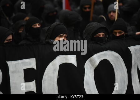 Vienne, Autriche. 13 Jan, 2018. mummed à capuchon et manifestants au cours d'une manifestation anti-gouvernementale portant une banderole. Credit : Vincent Sufiyan/Alamy Live News Banque D'Images