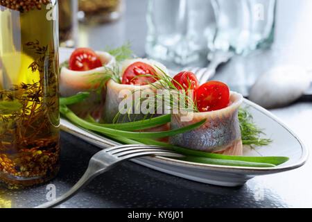 Filet de hareng de l'Atlantique dans l'huile. Roule avec de l'aneth , l'oignon vert et tomates cerises . Banque D'Images