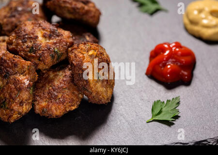 Dalle d'ardoise avec des boulettes à base de porc, de boeuf et de légumes avec la sauce tomate et la moutarde Banque D'Images