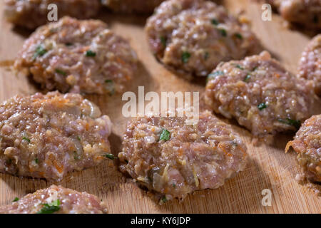 Boulettes de brut sur la planche à découper en bois. Petite profondeur de champ Banque D'Images