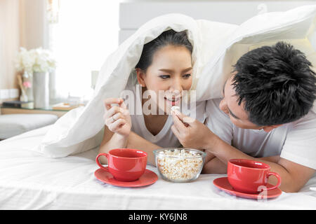 Les jeunes couples asiatiques de prendre le petit déjeuner sur le même lit dans la chambre de maison contemporaine de style moderne concept Banque D'Images