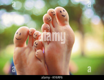 Smileys sur une paire de pieds sur tous les dix orteils dans un parc sur une chaude journée d'été Banque D'Images