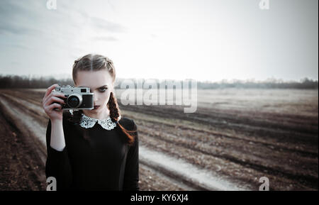 Jeune fille sérieuse photographier par la vieille caméra. Portrait en extérieur dans le domaine Banque D'Images