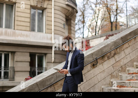 La moitié des jeunes guy nigérian restant avec tablet and looking at camera près de balustrade. Bel homme porte costume, watch, bagues, boucles et rosaire bouddhiste bra Banque D'Images