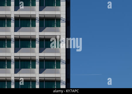 Image de fond d'un ciel bleu avec une façade de l'immeuble de bureau et une piste blanche à partir d'un avion dans le ciel. Banque D'Images