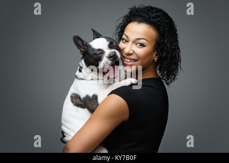 Belle Jeune femme tenant Bouledogue français chien. studio shot sur fond gris. copier l'espace. Banque D'Images
