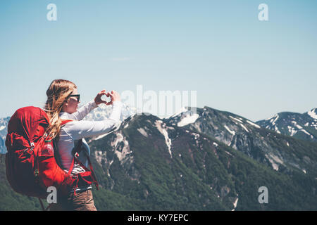 Happy Woman montrant l'amour du cœur par les mains de la randonnée dans les montagnes avec succès Vie Voyage sac à dos aventure en plein air vacances active concept Banque D'Images