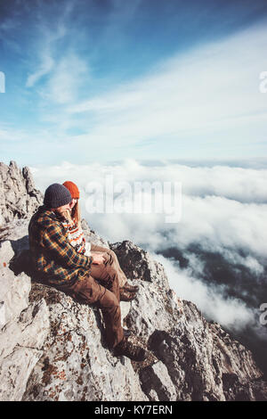 Voyageurs couple homme et femme assis sur des rochers en montagnes et nuages amour paysage avec une assurance vie émotions concept. Jeune famille Banque D'Images