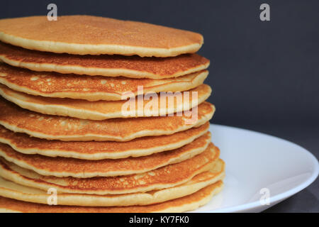 Vue de face de pile de crêpes maison plain sur plaque blanche sur fond noir avec selective focus Banque D'Images