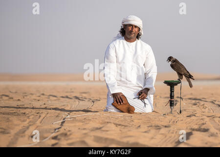 Abu Dhabi, UAE - Dec 15, 2017 : l'homme dans une robe traditionnelle emirati posant fièrement avec son spectacle formés falcon. Banque D'Images