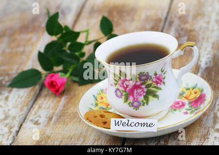 Carte de bienvenue avec tasse de thé en porcelaine vintage, cookie et rose rose Banque D'Images