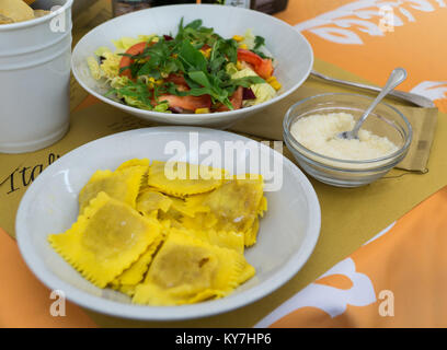 Ravioli farci avec de la citrouille (ravioli di Zucca) servi sur plaque blanche avec salade de style italien et le parmesan râpé dans un restaurant italien. Banque D'Images