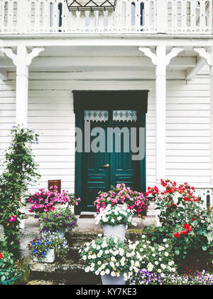 Maison de campagne en bois blanc porte d'entrée confortable avec terrasse extérieur fleurs décoration design et balcon bâtiment traditionnel de style rétro Banque D'Images