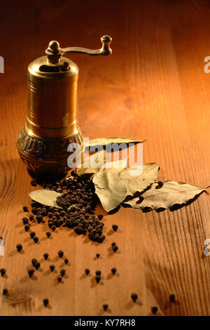 Vintage still life with brass moulin à poivre debout sur une table en bois près de feuilles de laurier et le poivre Banque D'Images