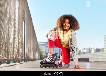 Happy African girl wearing inline skates et matériel de protection, l'exercice à rollerdrome Banque D'Images